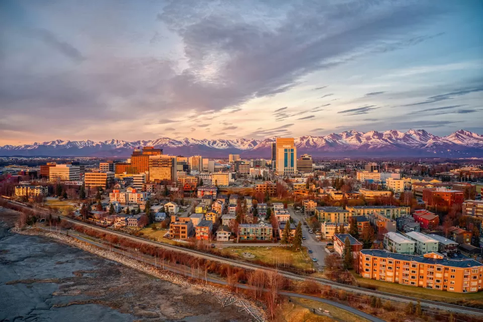 Aerial view of Anchorage, Alaska downtown with mountains in background at golden hour.